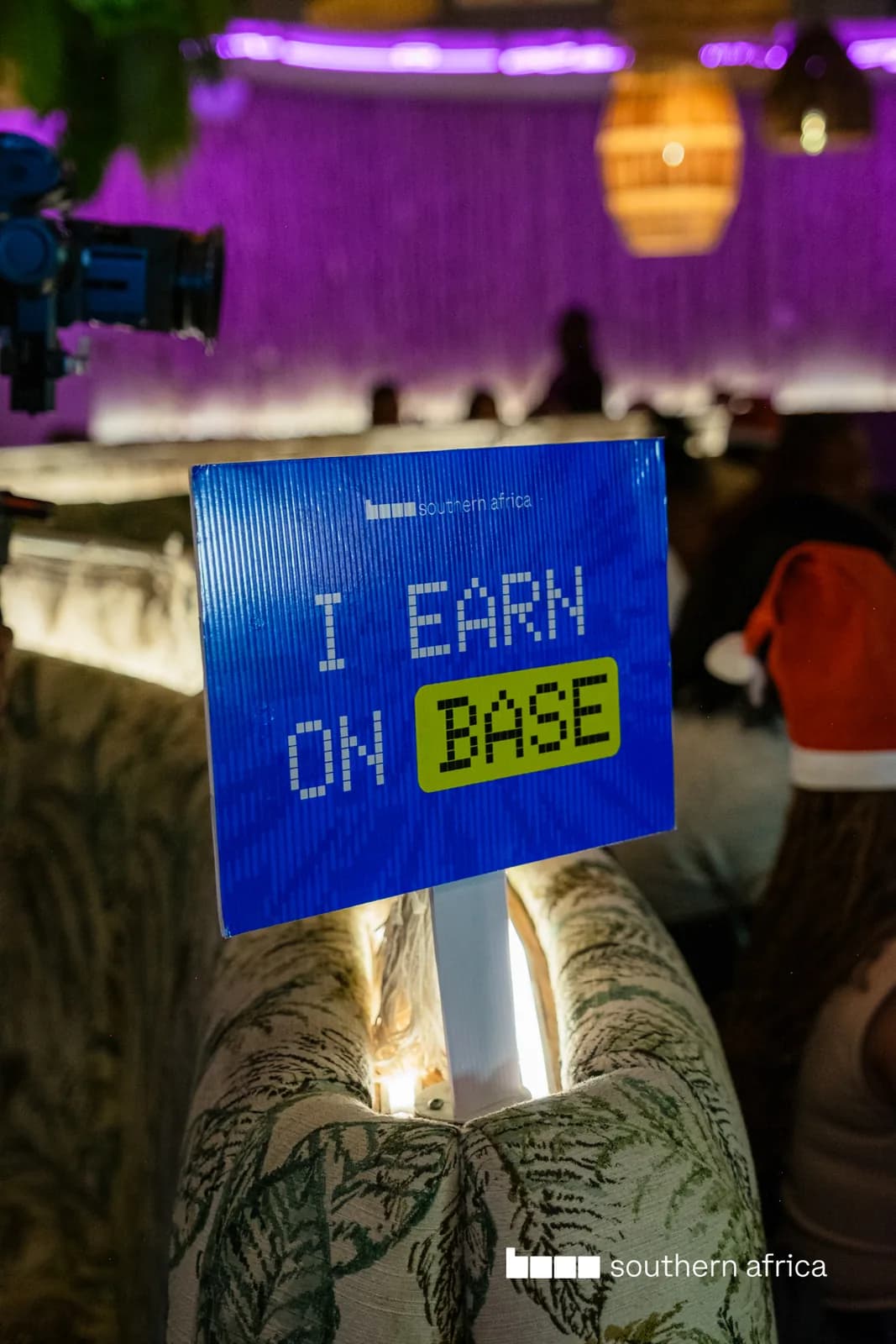 A hand holding an “I earn on Base” card at a Base event